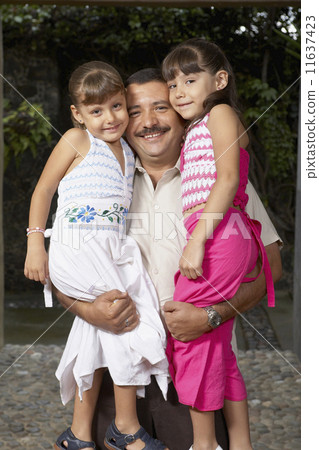 Hispanic father hugging daughters 11637423