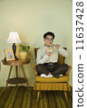 Nerdy Asian man eating in chair 11637428