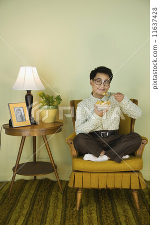 Nerdy Asian man eating in chair 11637428