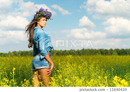 Beautiful young brunette in shorts and chaplet in a yellow field 11640420