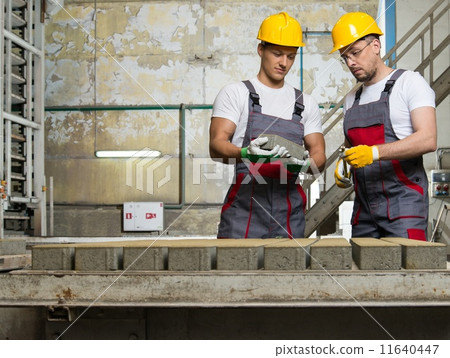 Worker and foreman in a safety hats performing quality check on a factory Worker and foreman in a safety hats performing quality check on a factory 11640447