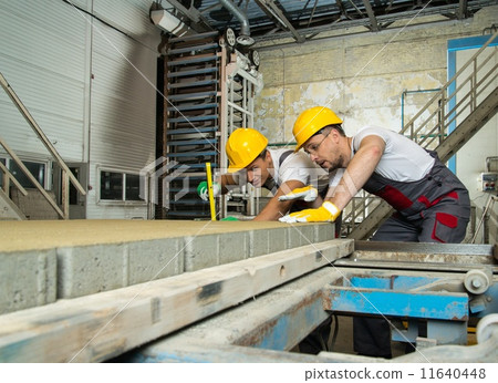 Worker and foreman in a safety hats performing quality check on a factory Worker and foreman in a safety hats performing quality check on a factory 11640448