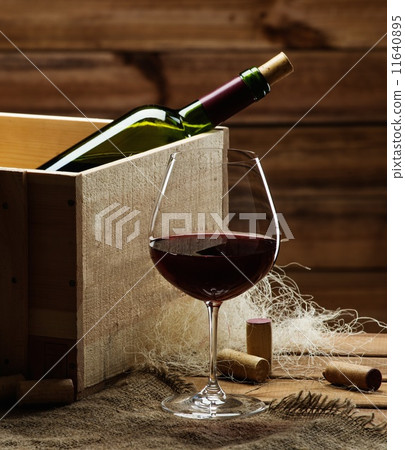 Bottle and glass of red wine on a wooden table 11640895