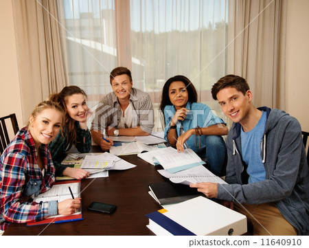 Multi ethnic group of students preparing for exams in home interior behind table Multi ethnic group of students preparing for exams in home interior behind table 11640910