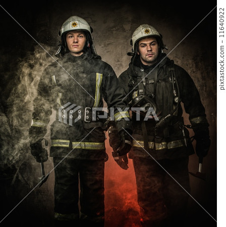 Two firefighters with helmet and axe in a smoke 11640922