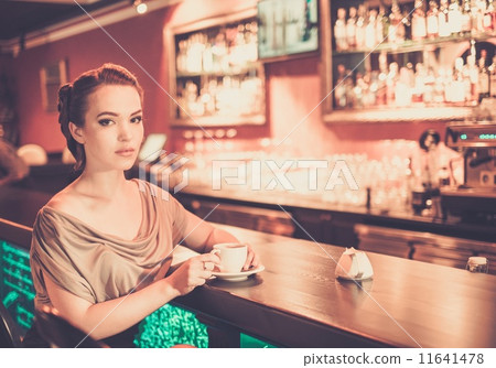 Beautiful young woman with cup of coffee near bar 11641478