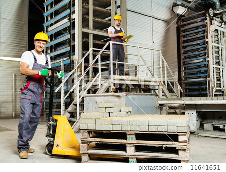 Young worker moving paving stones with pallet truck on a factory Young worker moving paving stones with pallet truck on a factory 11641651