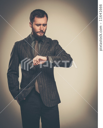 Handsome well-dressed man with beard looking at his wrist watch 11641666