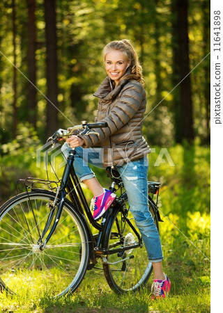 Cheerful teenage girl listens music on a bicycle outdoors 11641898