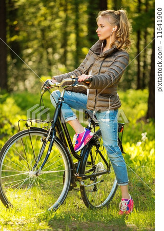 Cheerful teenage girl listens music on a bicycle outdoors Cheerful teenage girl listens music on a bicycle outdoors 11641900