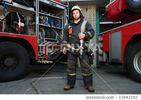 Firefighter near truck with equipment with water water hose over shoulder 11642102