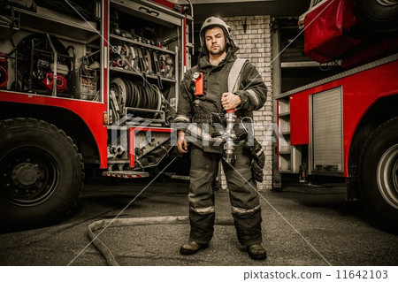 Firefighter near truck with equipment with water water hose over shoulder 11642103