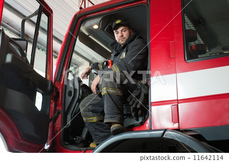 Fireman behind steering wheel of a firefighting truck Fireman behind steering wheel of a firefighting truck 11642114