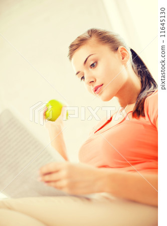 woman with green apple reading newspaper at home woman with green apple reading newspaper at home 11645130