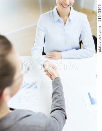 two smiling businesswoman shaking hands in office 11645306