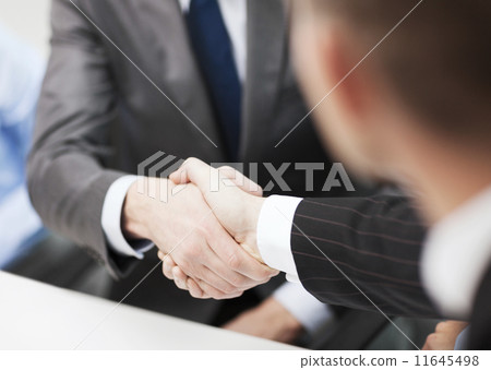 two businessmen shaking hands in office 11645498