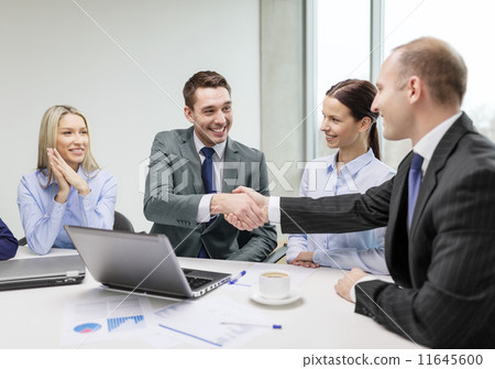 two businessman shaking hands in office 11645600
