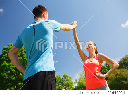 two smiling people making high five outdoors 11646034