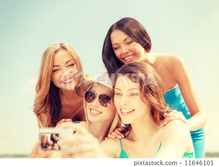 smiling girls taking photo in cafe on the beach 11646101