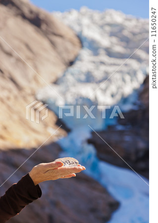 Hand with ice and Briksdal glacier - Norway 11650247