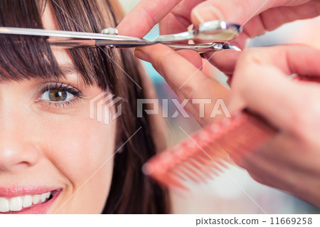 Hairdresser cutting woman bangs hair in shop 11669258