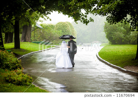 Couple under umbrella walking away on road at park 11670694