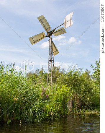 Small and rusted old metal windmill at the waterside Small and rusted old metal windmill at the waterside 11673067