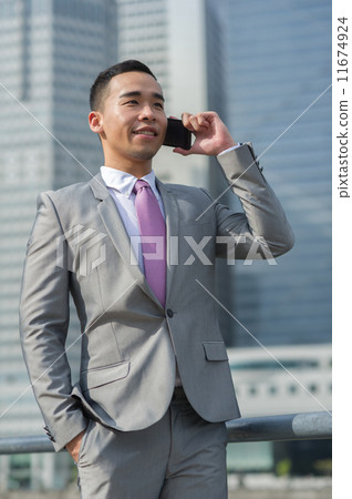 A young and dynamic businessman / banker in suit taking on the mobile device/ phone A young and dynamic businessman / banker in suit taking on the mobile device/ phone 11674924