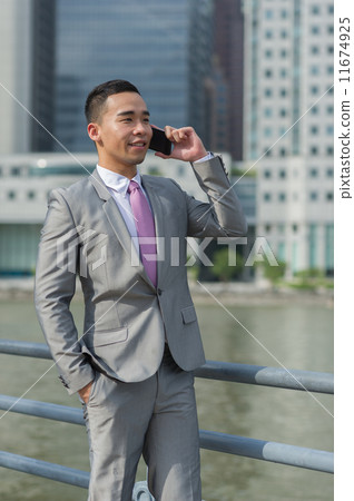 A young and dynamic businessman / banker in suit taking on the mobile device/ phone 11674925