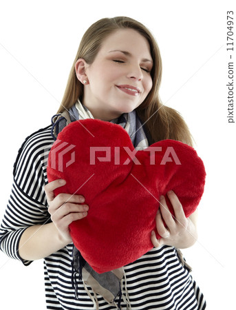 Beautyful young and smiling woman embraces heart shaped pillow with her hands Beautyful young and smiling woman embraces heart shaped pillow with her hands 11704973