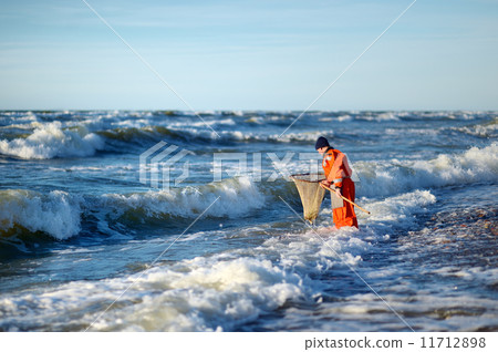 Man with landing net looking for amber on a sea Man with landing net looking for amber on a sea 11712898