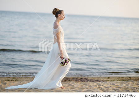 Bride walking along sea coast on sunset 11714466