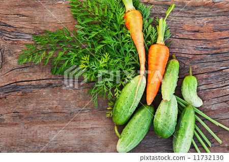 Ripe green cucumbers and carrots on old wooden background. 11732130