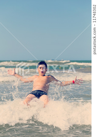 Happy boy running and jumping at shallow sea water 11748302