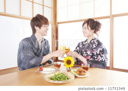 A man and a woman in a yukata that toast a beer in a Japanese style room 11751349