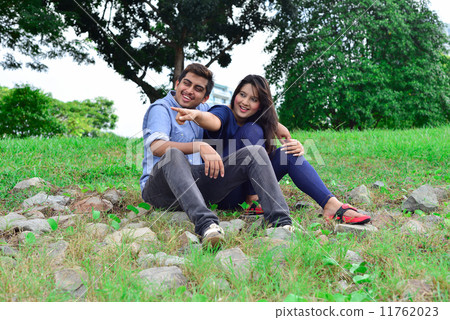 A young and beautiful asian lady pointing at a direction to her boyfriend while they were seated 11762023