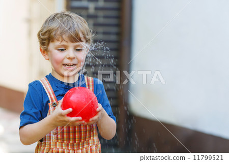 Little toddler boy having fun with splashing water in summer gar 11799521