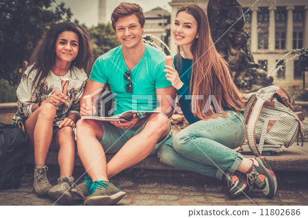 Group of multi ethnic students with ice-cream near fountain in a city park 11802686