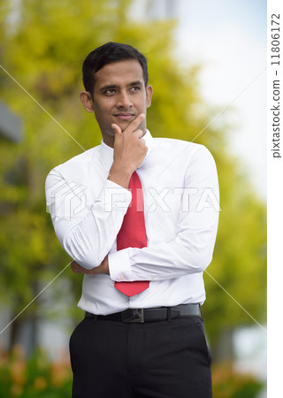 Portrait of successful young Indian corporate executive standing along promenade Portrait of successful young Indian corporate executive standing along promenade 11806172