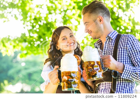 German couple in Tracht drinking beer 11809224