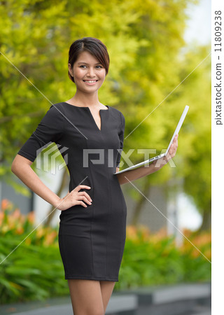 Successful young Malay business woman using laptop along promenade Successful young Malay business woman using laptop along promenade 11809238