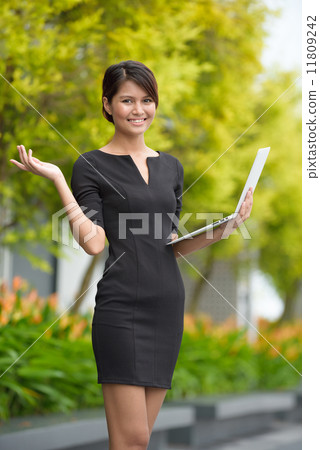 Successful young Malay business woman presenting using laptop along promenade Successful young Malay business woman presenting using laptop along promenade 11809242