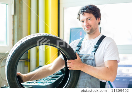 Auto mechanic changing tire in car workshop Auto mechanic changing tire in car workshop 11809402