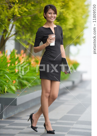 Successful young Malay business woman with coffee cup and laptop along promenade during break time Successful young Malay business woman with coffee cup and laptop along promenade during break time 11809550