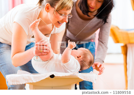 Midwife measuring weight or newborn baby 11809558