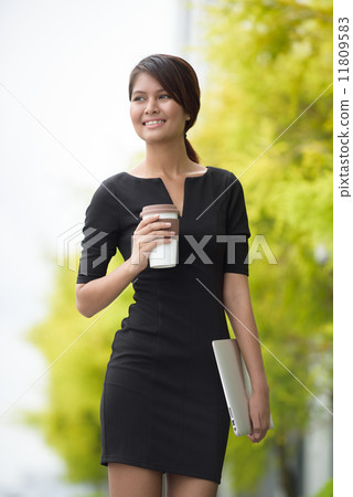 Successful young Malay business woman with coffee cup and laptop along promenade during break time 11809583