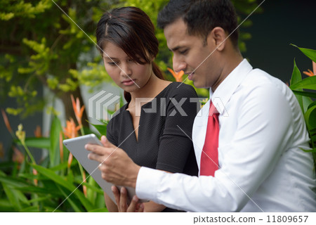 Mix race successful Indian Malay corporate execute meeting using iPad mobile device tablet outdoor Mix race successful Indian Malay corporate execute meeting using iPad mobile device tablet outdoor 11809657