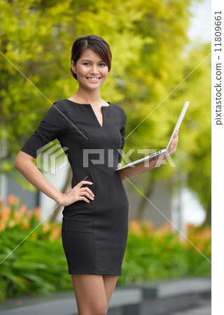 Successful young Malay business woman using laptop along promenade Successful young Malay business woman using laptop along promenade 11809661