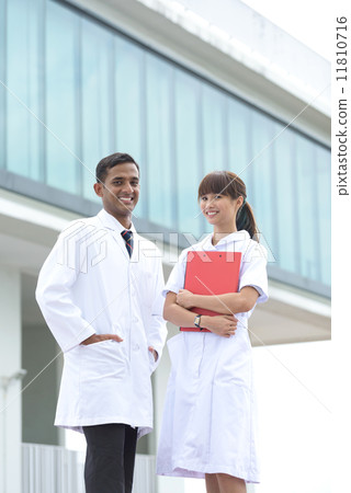 Successful young mixed race medical doctor and nurse standing in front of hospital 11810716