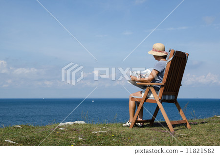 Woman reading newspaper in a chair with beautiful view Woman reading newspaper in a chair with beautiful view 11821582